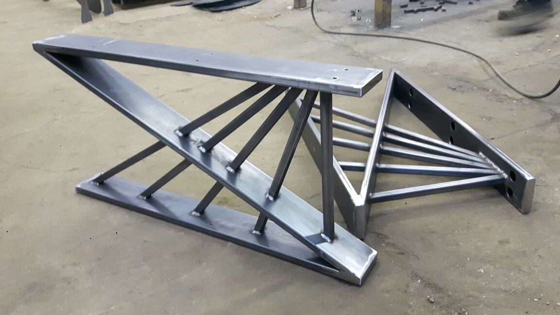 Металлические ножки для стола, выполненные с высокой точностью, лежат на полу мастерской.